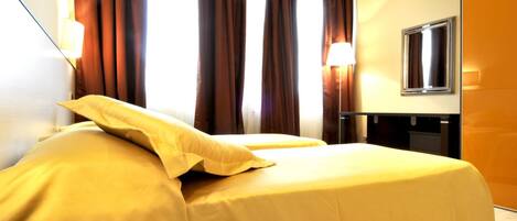 Una habitación de hotel con cama, cortinas, lámpara y espejo.