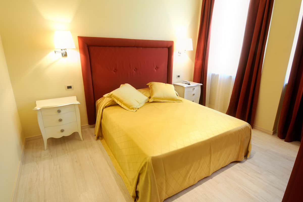 A hotel room with a bed, two bedside tables, and a nightstand.