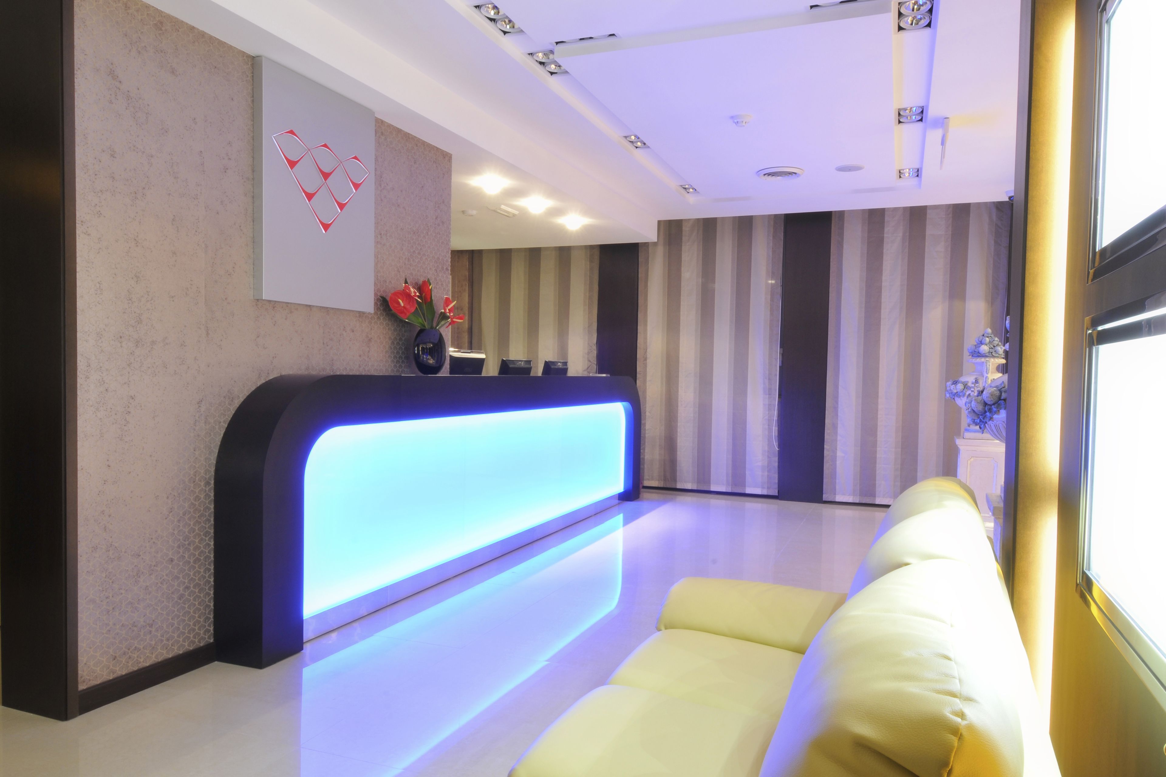 A reception area with a modern reception desk, a sofa, and a striped wall in the background.
