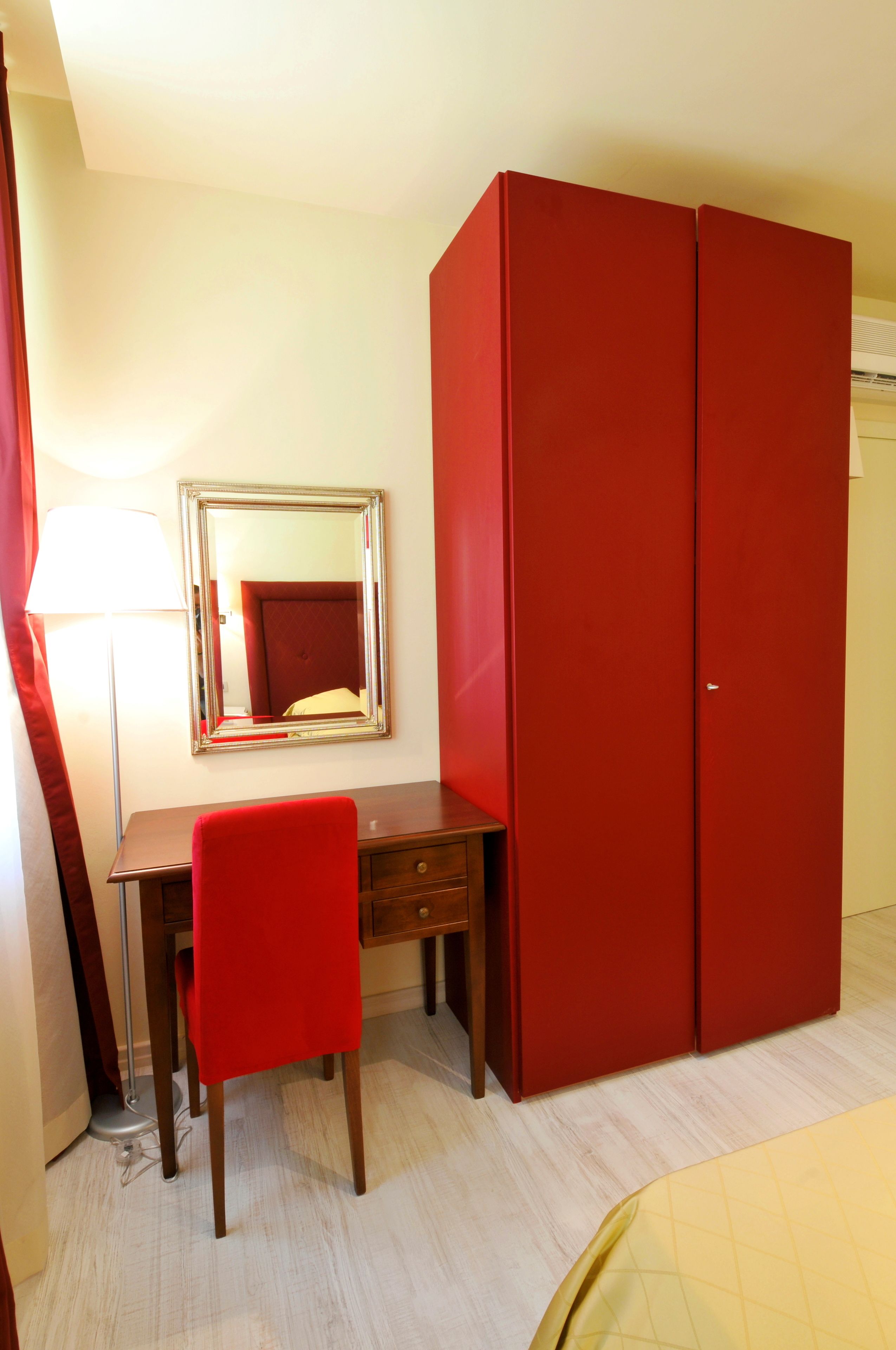 Een kamer met een bureau, stoel en een grote rode garderobe.