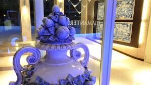 A decorative urn with floral patterns and a pedestal base, displayed in a well-lit indoor setting. - Residence Diamanterosso (Terni)