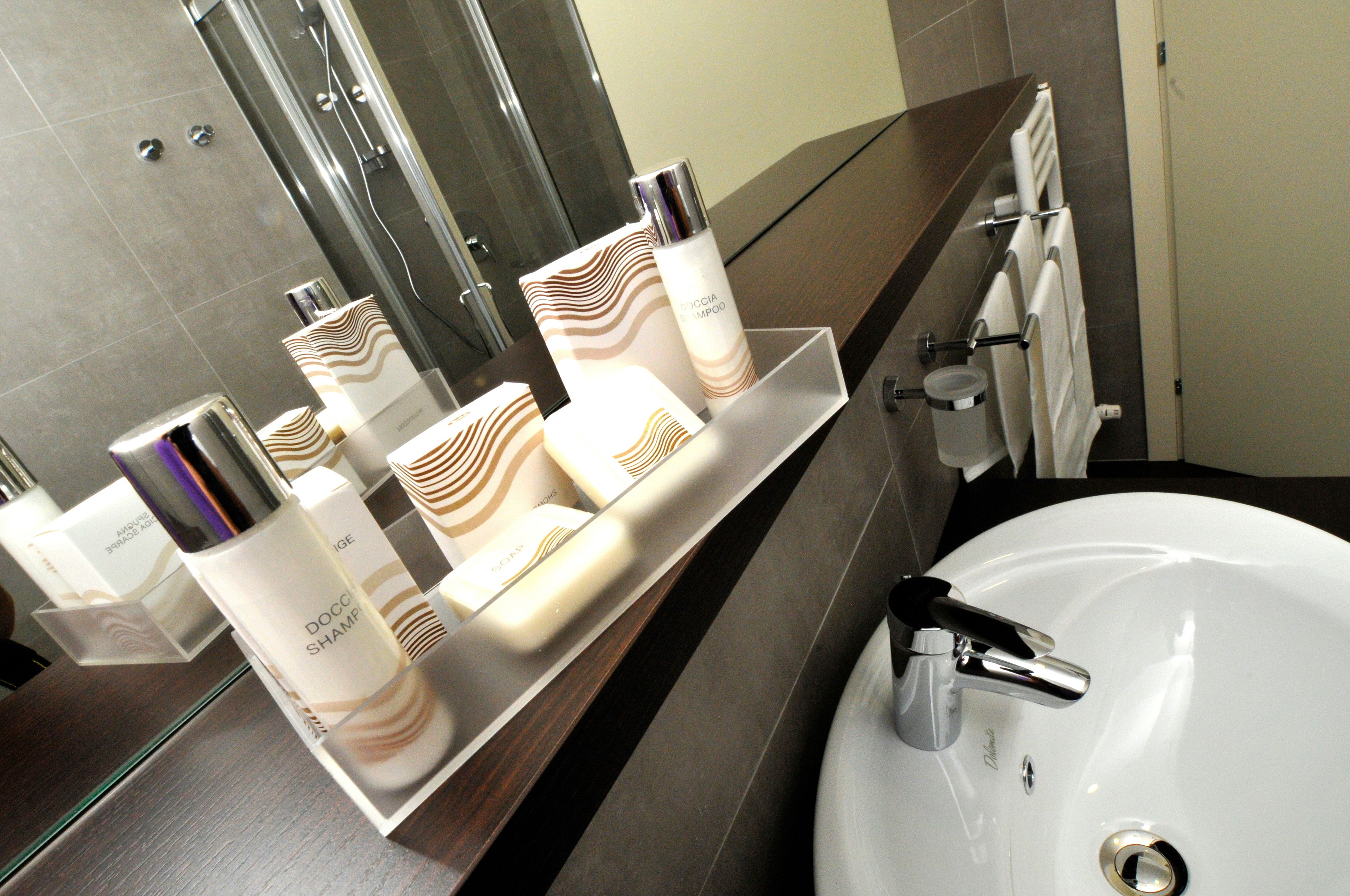 Ein Badezimmer mit einem weißen Waschbecken, einem Spiegel und Pflegeprodukten auf einem Regal.