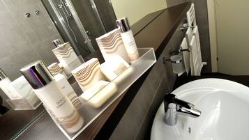 A bathroom with a white sink, a mirror, and toiletries on a shelf.