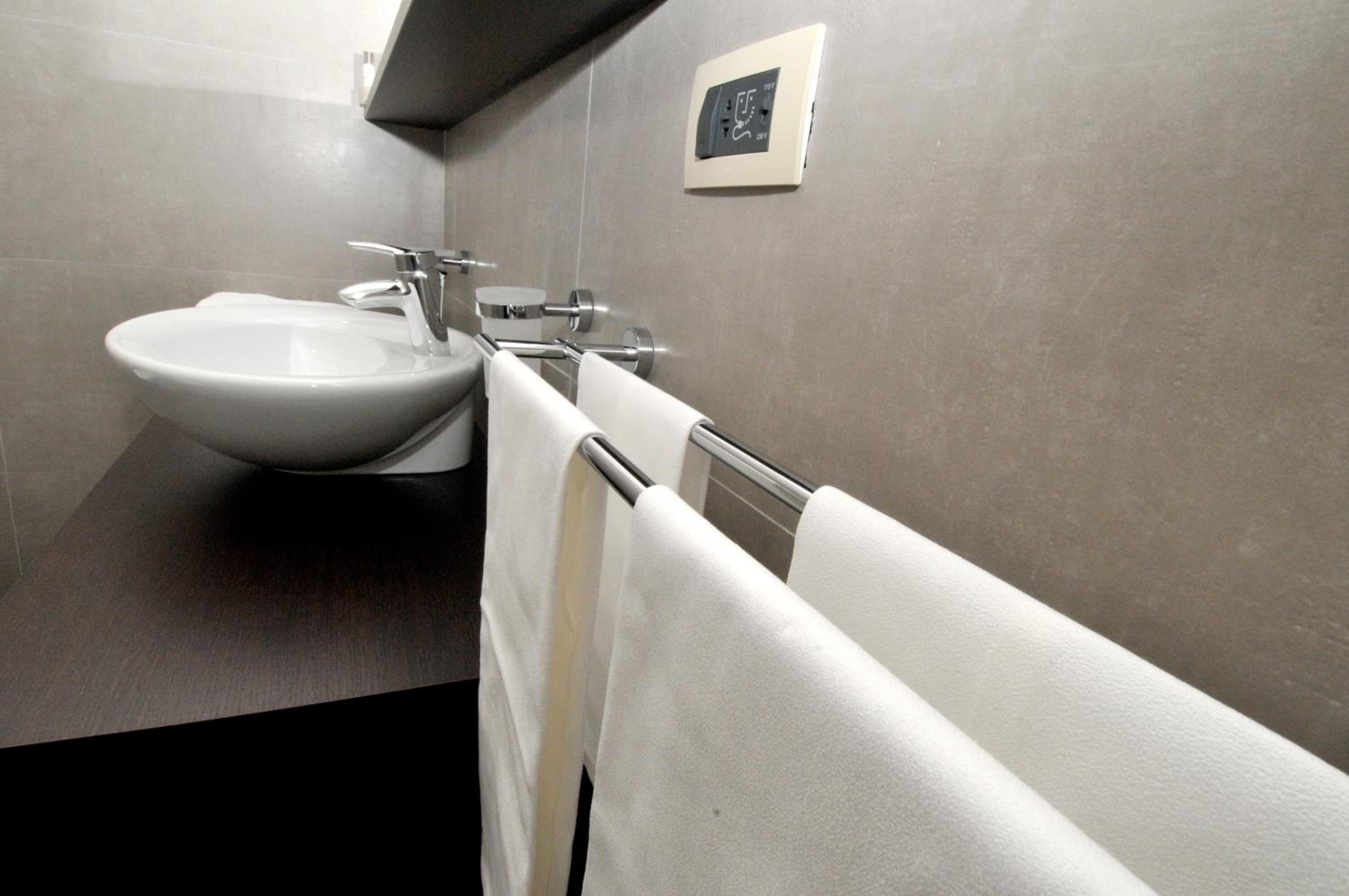 Un baño moderno con un lavamanos grande, toallero y termostato instalado en la pared.