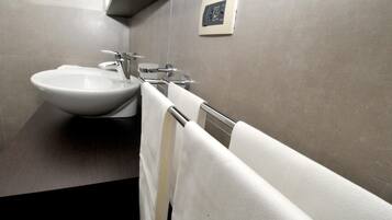 Un bagno moderno con un lavandino ampio, un porta asciugamani e un termostato a parete.