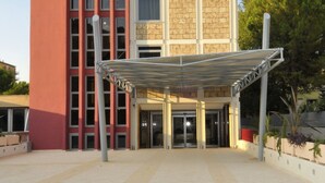 A modern building with a red facade and a covered entrance area. - Residence Diamanterosso (Terni)