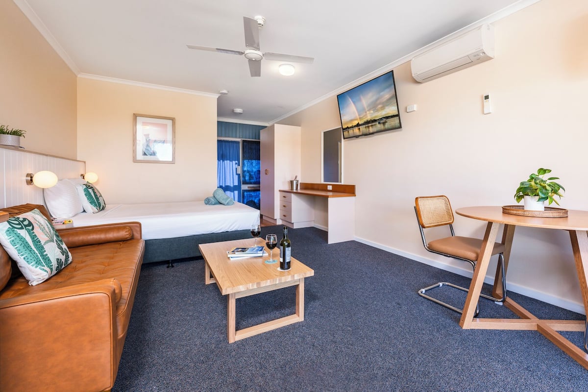 A hotel room with a bed, a sofa, a small table, a chair, and a desk.