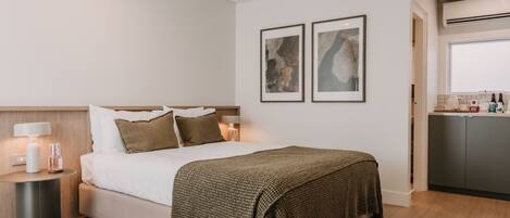 A bedroom with a bed, bedside lamps, a bedside table, a headboard, and a wall-mounted artwork.