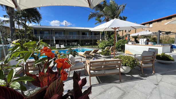Un espace aménagé au bord de la piscine, avec des chaises longues, des parasols et un comptoir d’accueil.