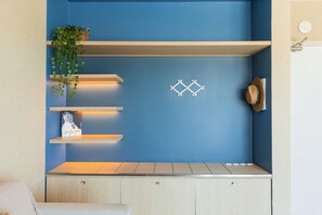 A room with a blue accent wall, wooden shelves, a plant, and a hat on the wall. - Palace Praia Hotel (Florianópolis)