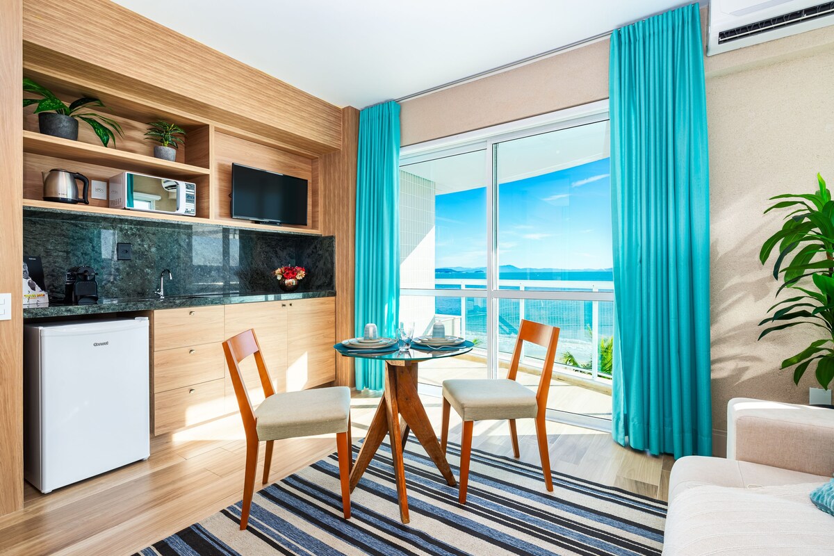 A modern kitchen with a built-in TV, a small fridge, and a dining area with a table and chairs.