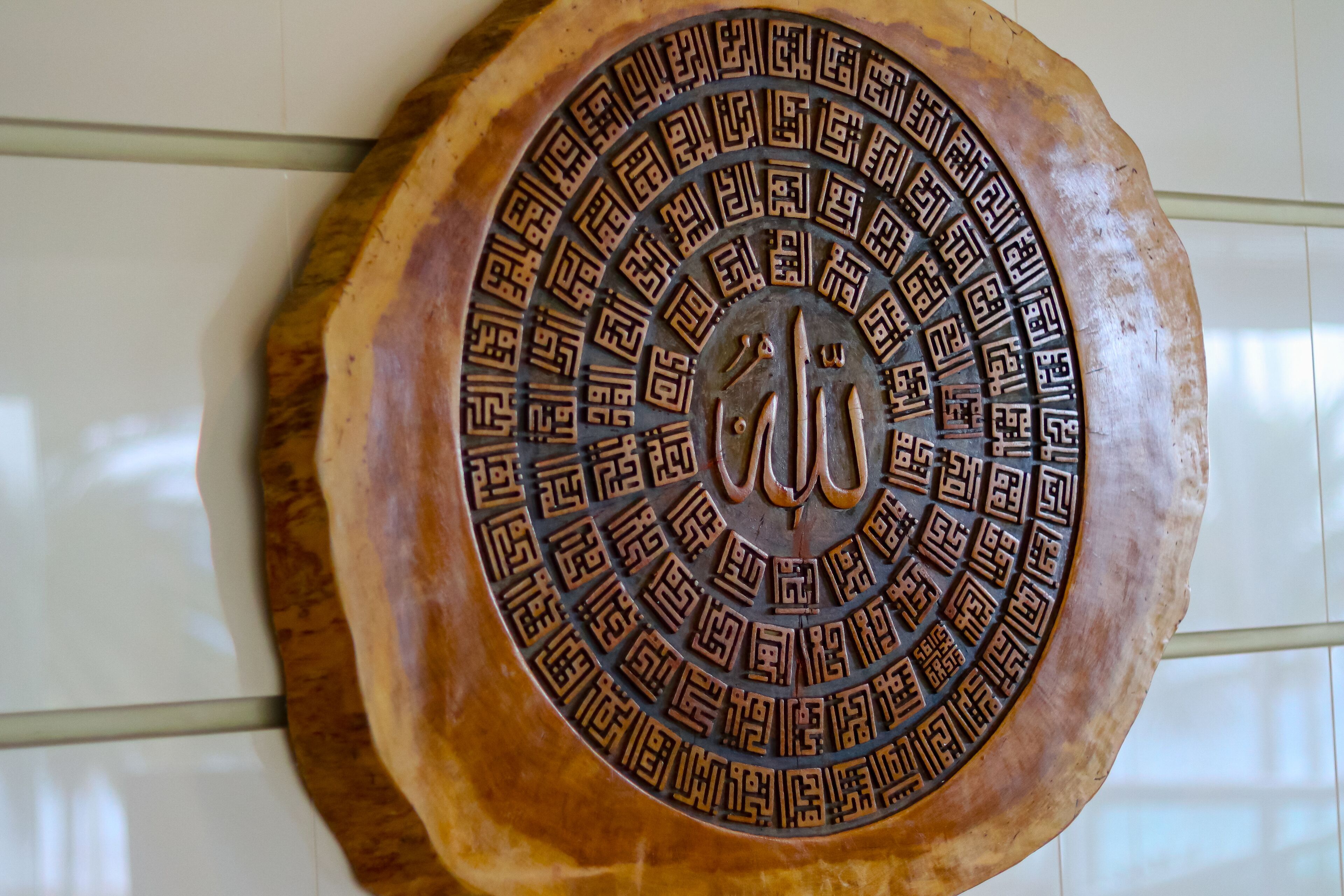A decorative metal plaque with intricate patterns and Arabic calligraphy.
