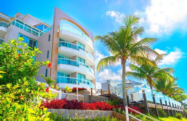 A modern multi-story hotel with balconies, surrounded by lush greenery and palm trees. - Palace Praia Hotel (Florianópolis)