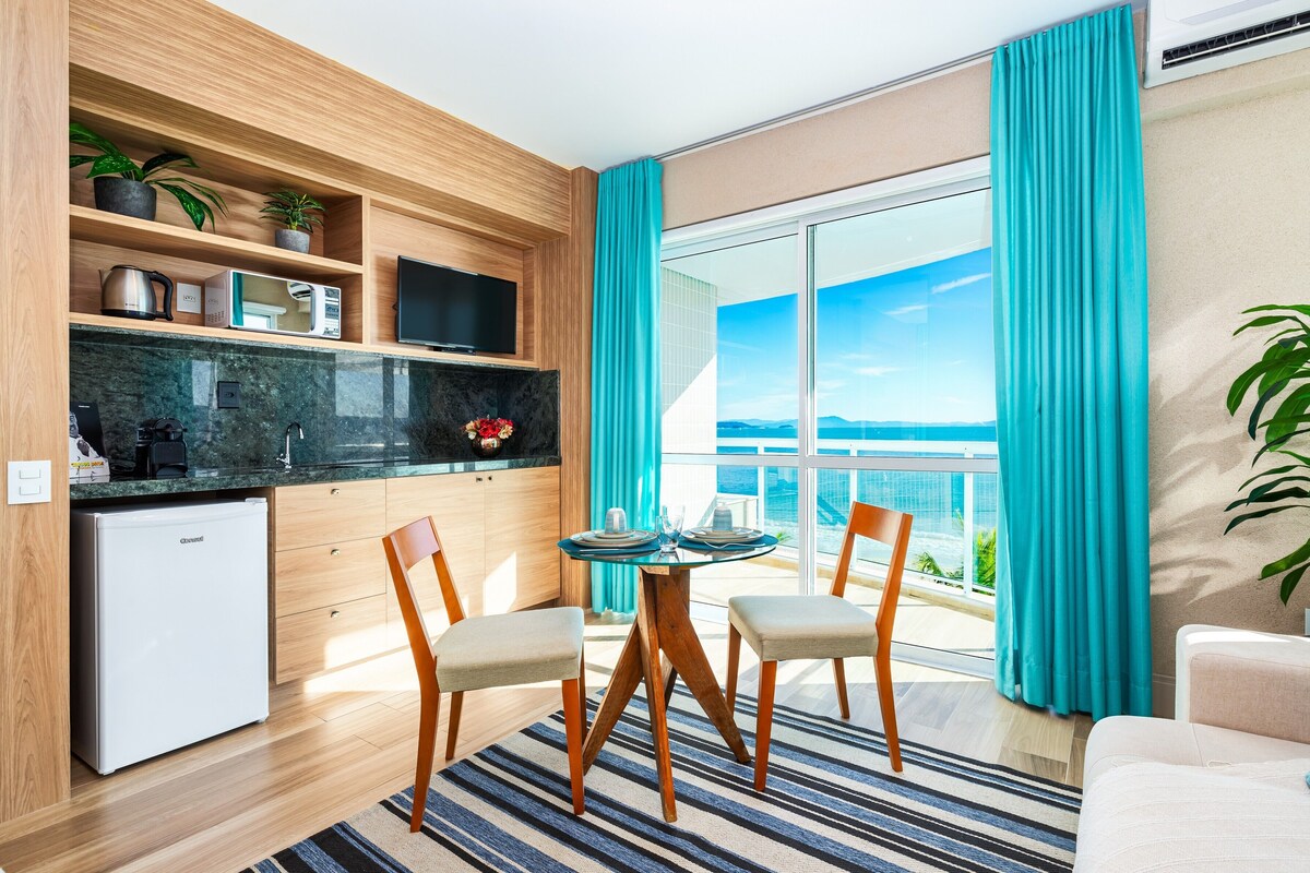 A modern kitchen with a built-in TV, a small fridge, and a dining area with a table and chairs.