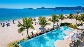 A poolside view with a beach and ocean in the background. - Palace Praia Hotel (Florianópolis)