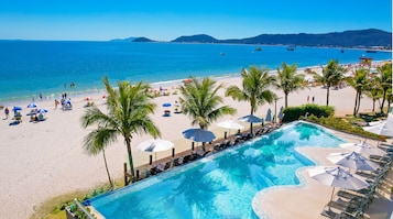 A poolside view with a beach and ocean in the background.