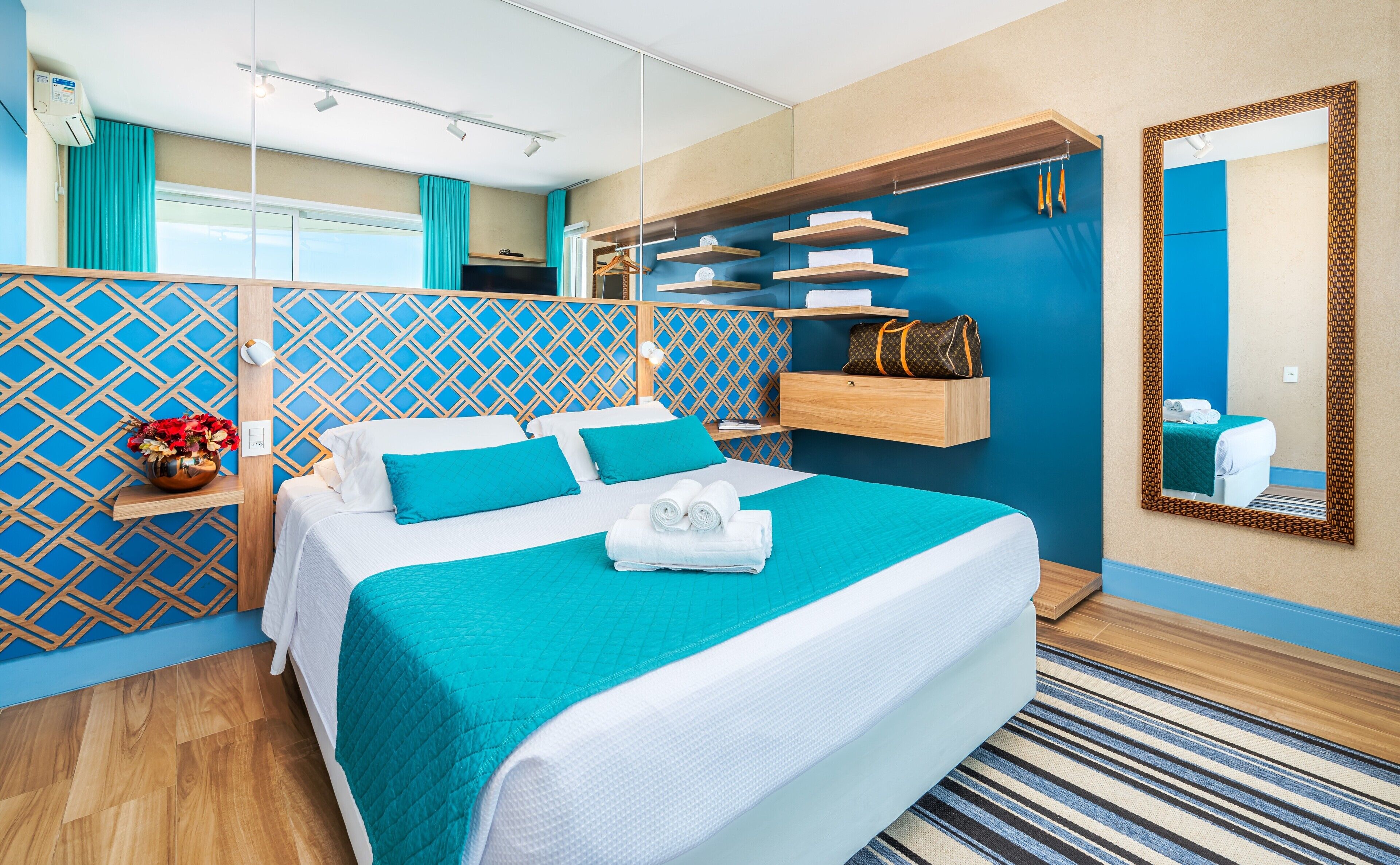 Une chambre d’hôtel moderne dotée d’un grand lit, d’une armoire intégrée, d’une coiffeuse avec miroir et offrant une vue sur l’extérieur.