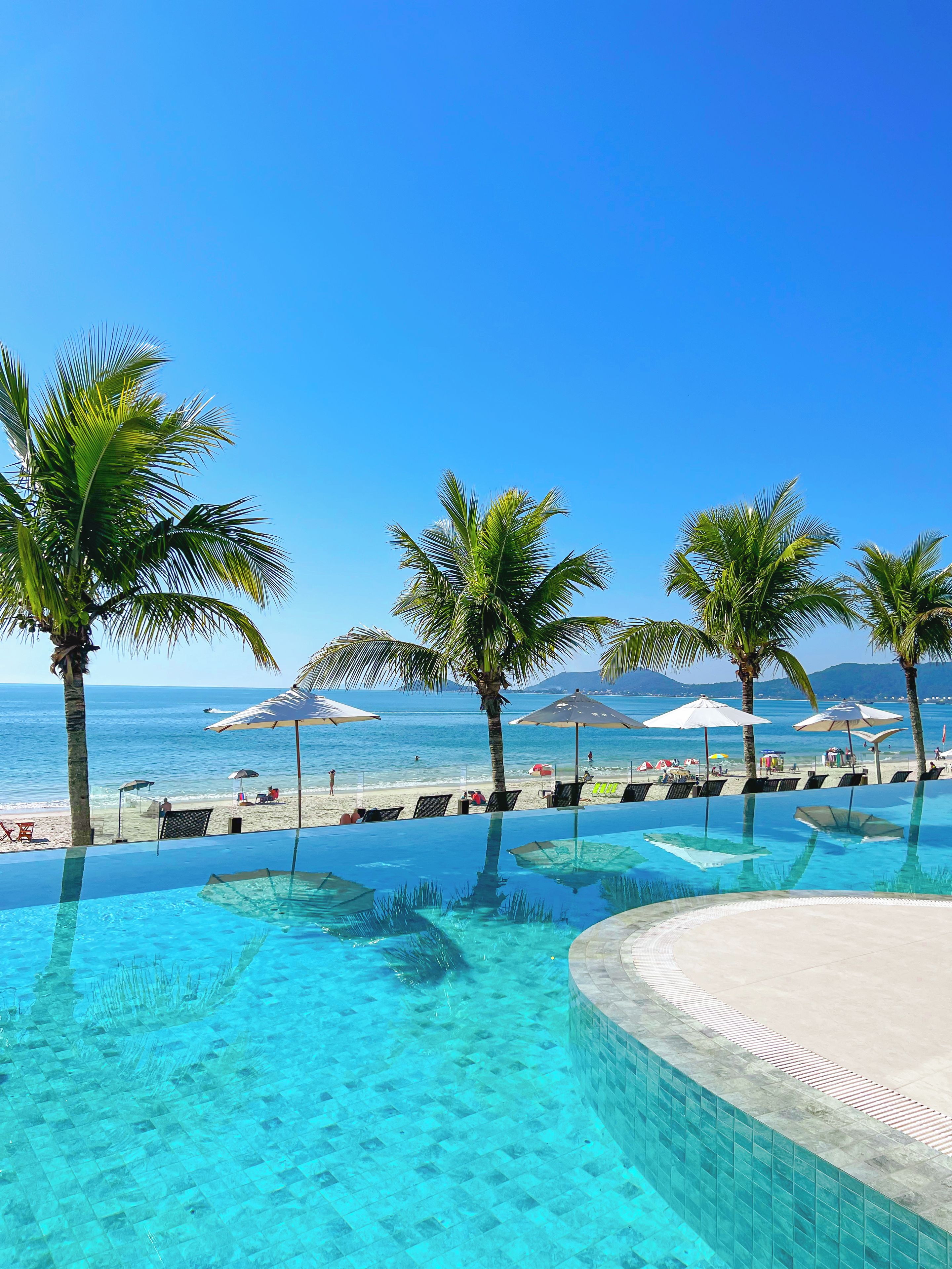 A clear blue pool with a view of the beach and ocean.