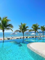 A clear blue pool with a view of the beach and ocean.
