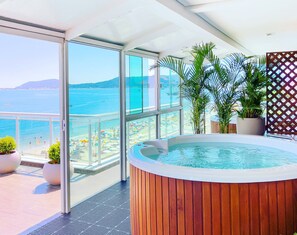 A balcony with a hot tub, large windows, and potted plants. - Palace Praia Hotel (Florianópolis)