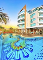 Un hotel con piscina caratterizzata da un mosaico colorato, diversi balconi e uno stile architettonico moderno.