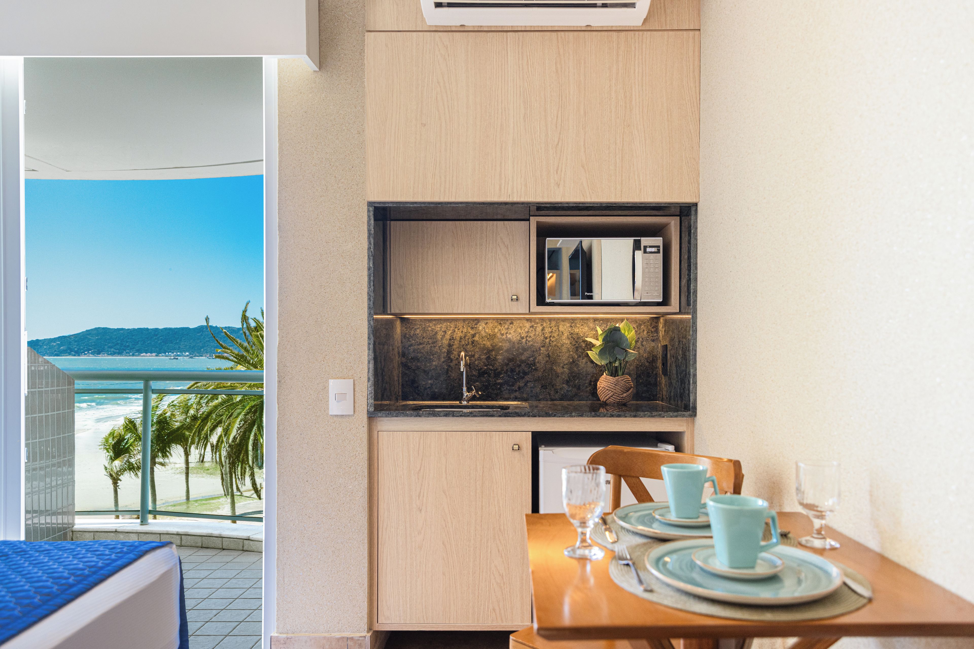 A compact kitchenette with a built-in microwave, a small sink, and a countertop with a potted plant.