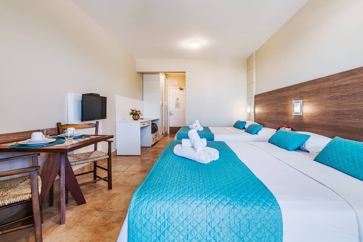 Une chambre d’hôtel avec un lit, un bureau, une chaise et un téléviseur.