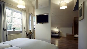 A bedroom with a large bed, a TV mounted on the wall, and a window with curtains. - Fosshotel Hekla (Selfoss)
