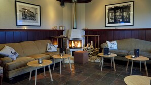 A cozy lounge area with a fireplace, sofas, and tables. - Fosshotel Hekla (Selfoss)