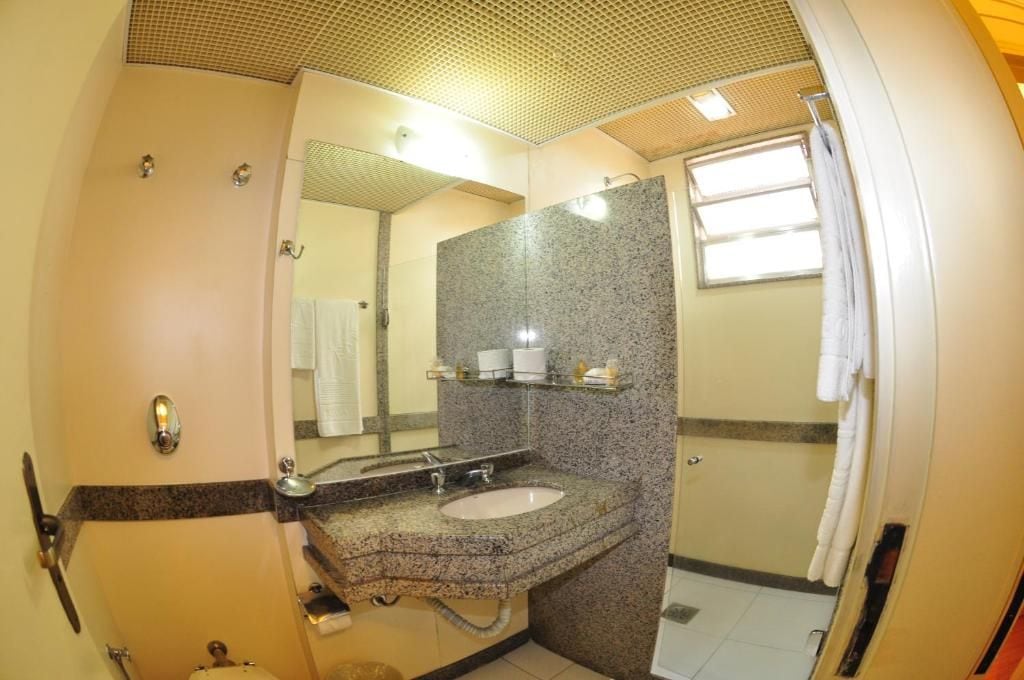 Baño con lavamanos de encimera de granito, espejo, toallero y zona de ducha.