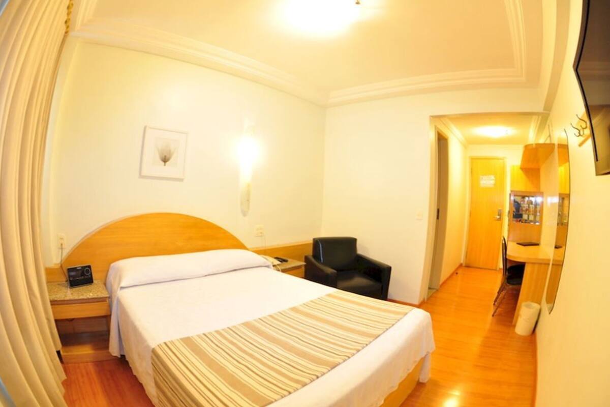 Une chambre d’hôtel avec un lit simple, une chaise, un bureau et un miroir.