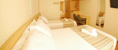 A hotel room with two beds, a desk, a chair, and a mirror.