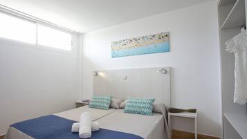 Una habitación de hotel con una cama, una mesita de noche, un cuadro y un armario.