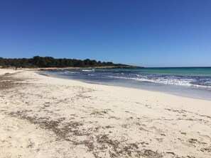 A beach with clear blue water, sandy shore, and a forested hill in the background. - BJ Apartamentos Club Sa Coma (Sant Llorenc des Cardassar)