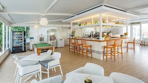 A spacious indoor area with a pool table, bar area with stools, and a vending machine. - BJ Apartamentos Club Sa Coma (Sant Llorenc des Cardassar)