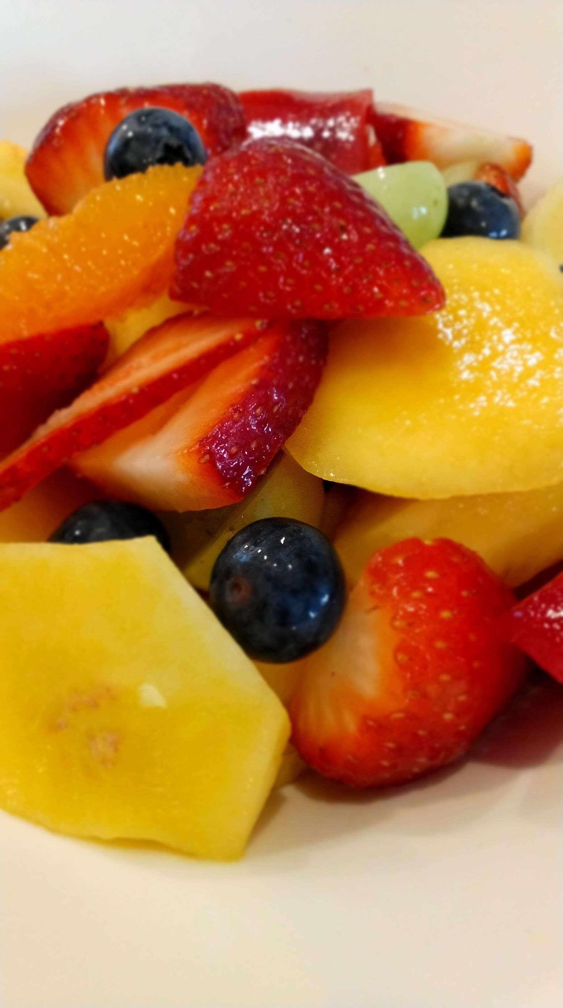 A close-up of a fruit salad with strawberries, blueberries, and pineapple.