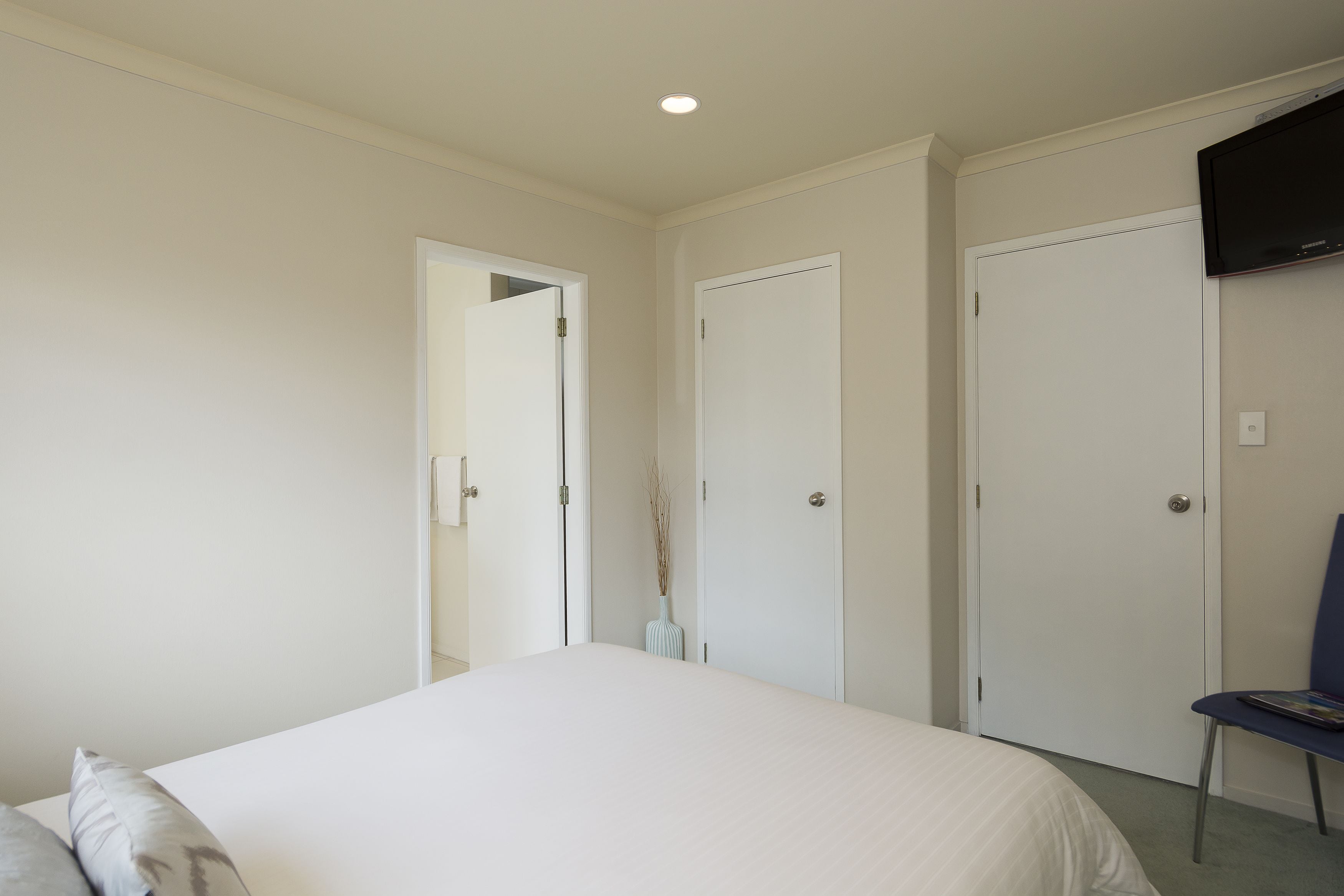 A bedroom with a bed, a chair, and two doors.