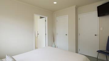 A bedroom with a bed, a chair, and two doors.