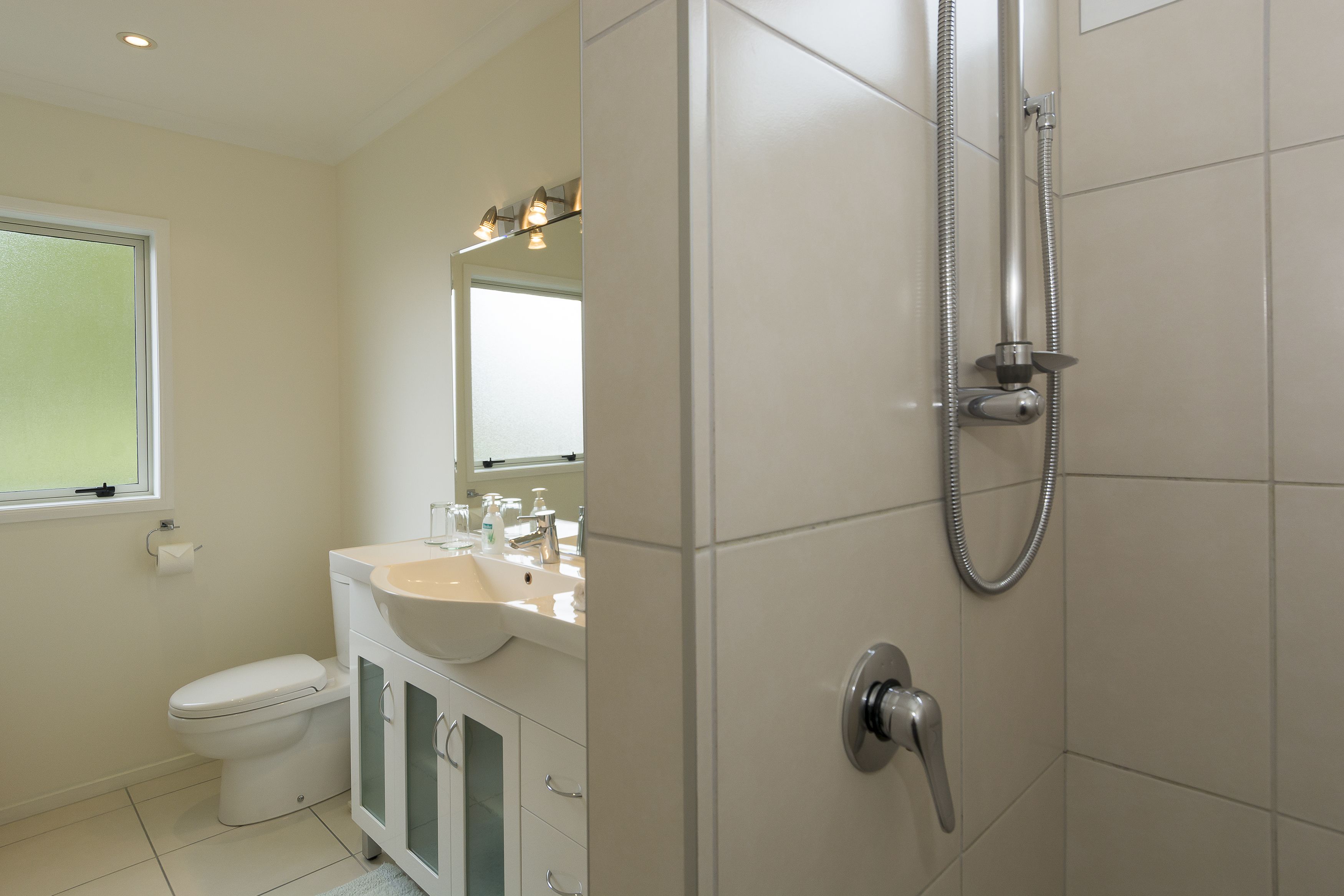 Een moderne badkamer met toilet, wastafel en douche.