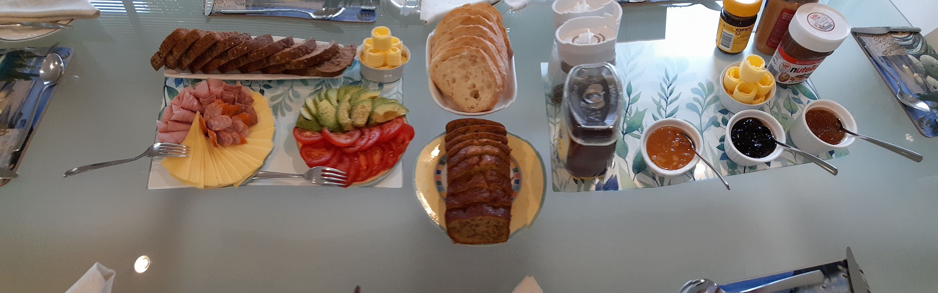 A table with various food items including sliced bread, cheese, tomatoes, and condiments.