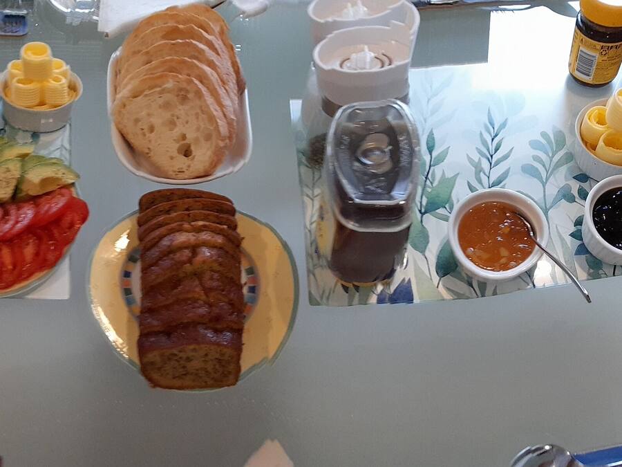 A table with various food items including sliced bread, cheese, tomatoes, and condiments.