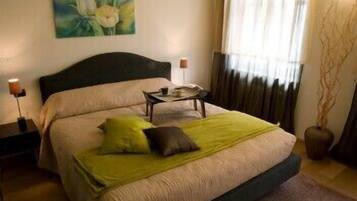 A neatly arranged bedroom with a bed, a bedside table, a lamp, and a painting on the wall.