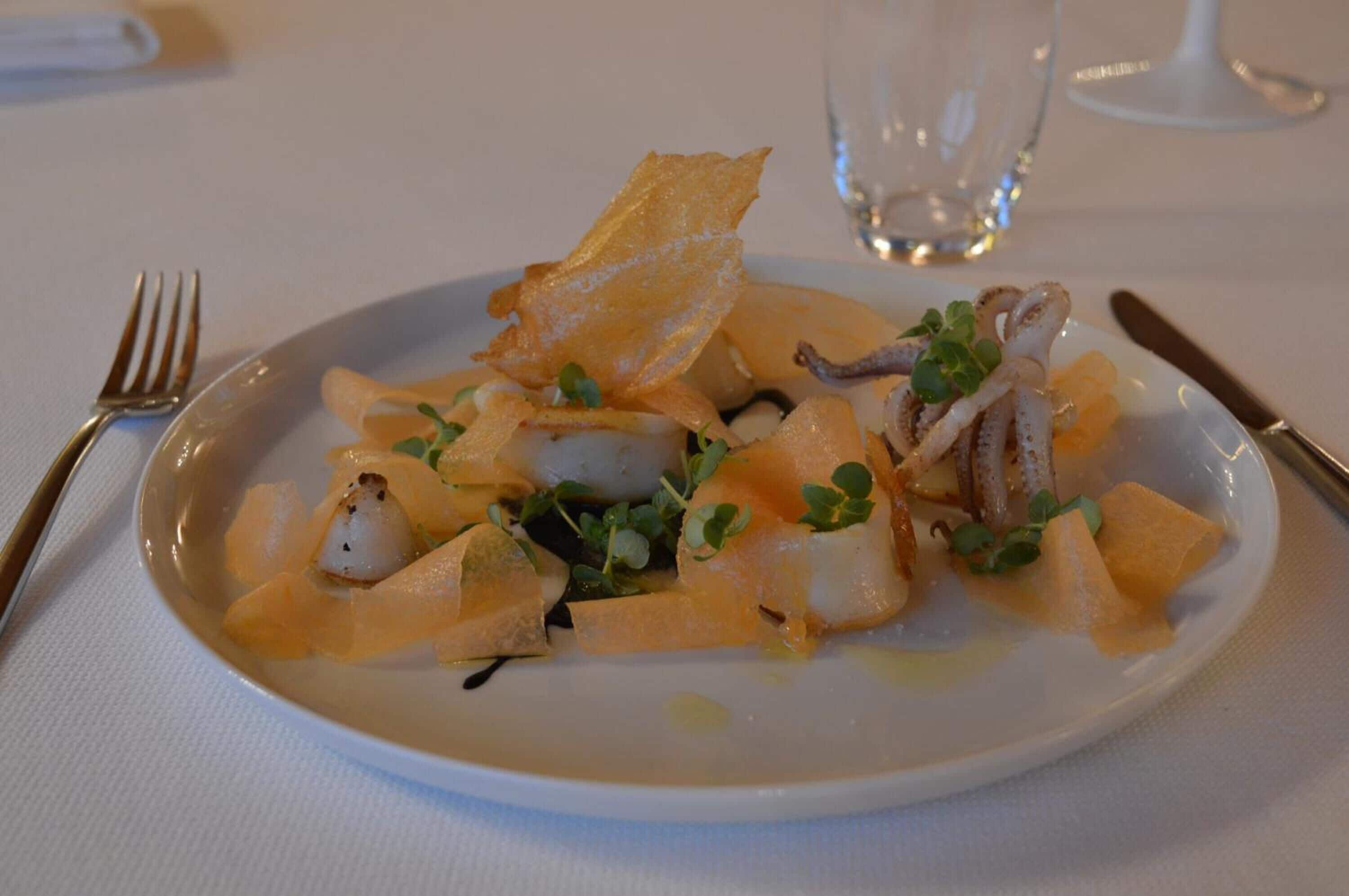 A plate of food with various ingredients, a fork, and a knife on a table.