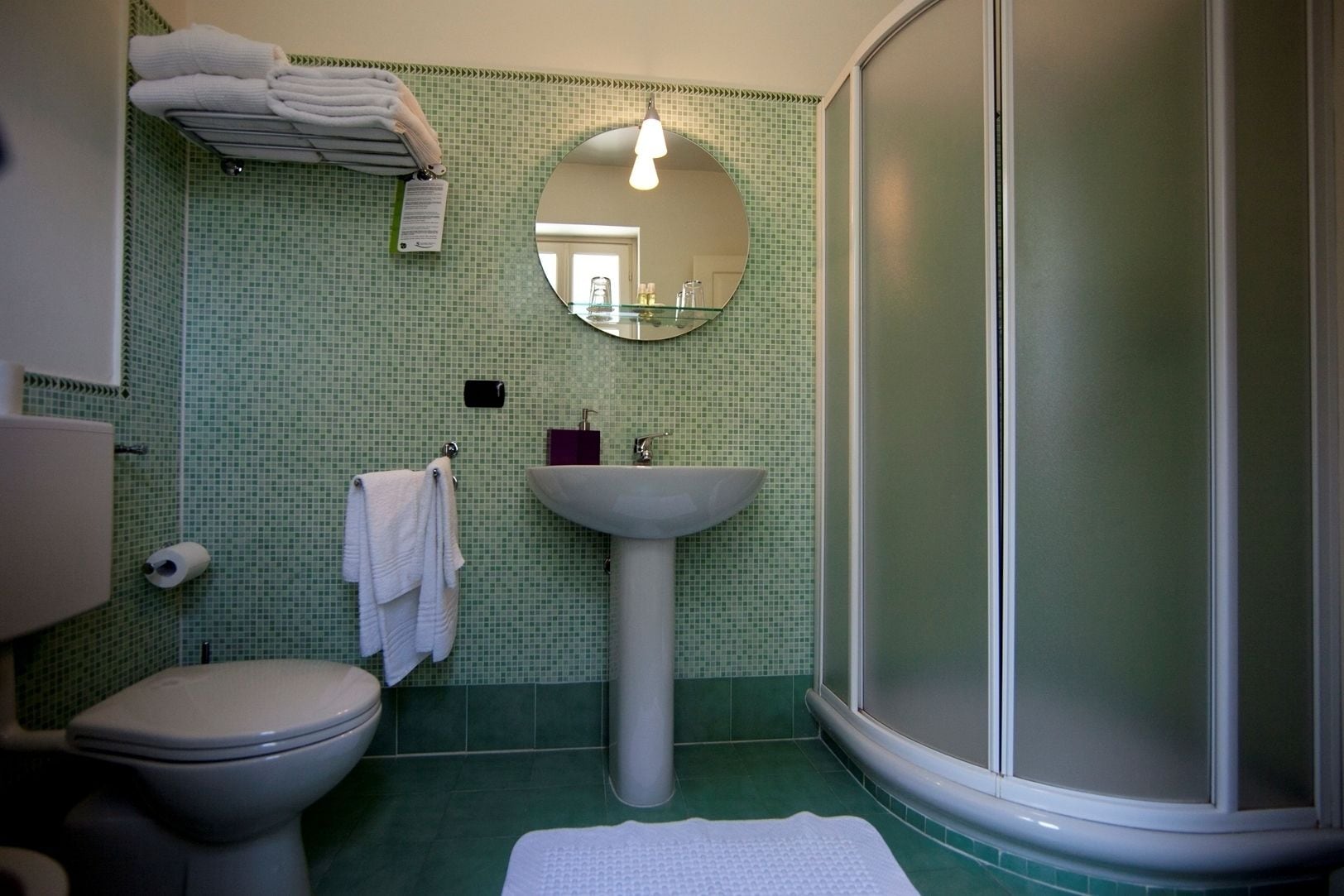 A bathroom with a toilet, sink, and shower.