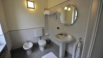 A bathroom with a toilet, bidet, sink, and a mirror.