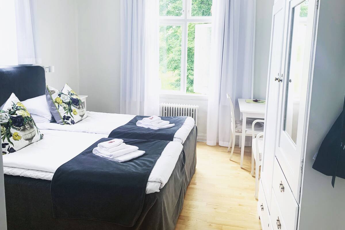 A hotel room with two beds, a desk, and a wardrobe.