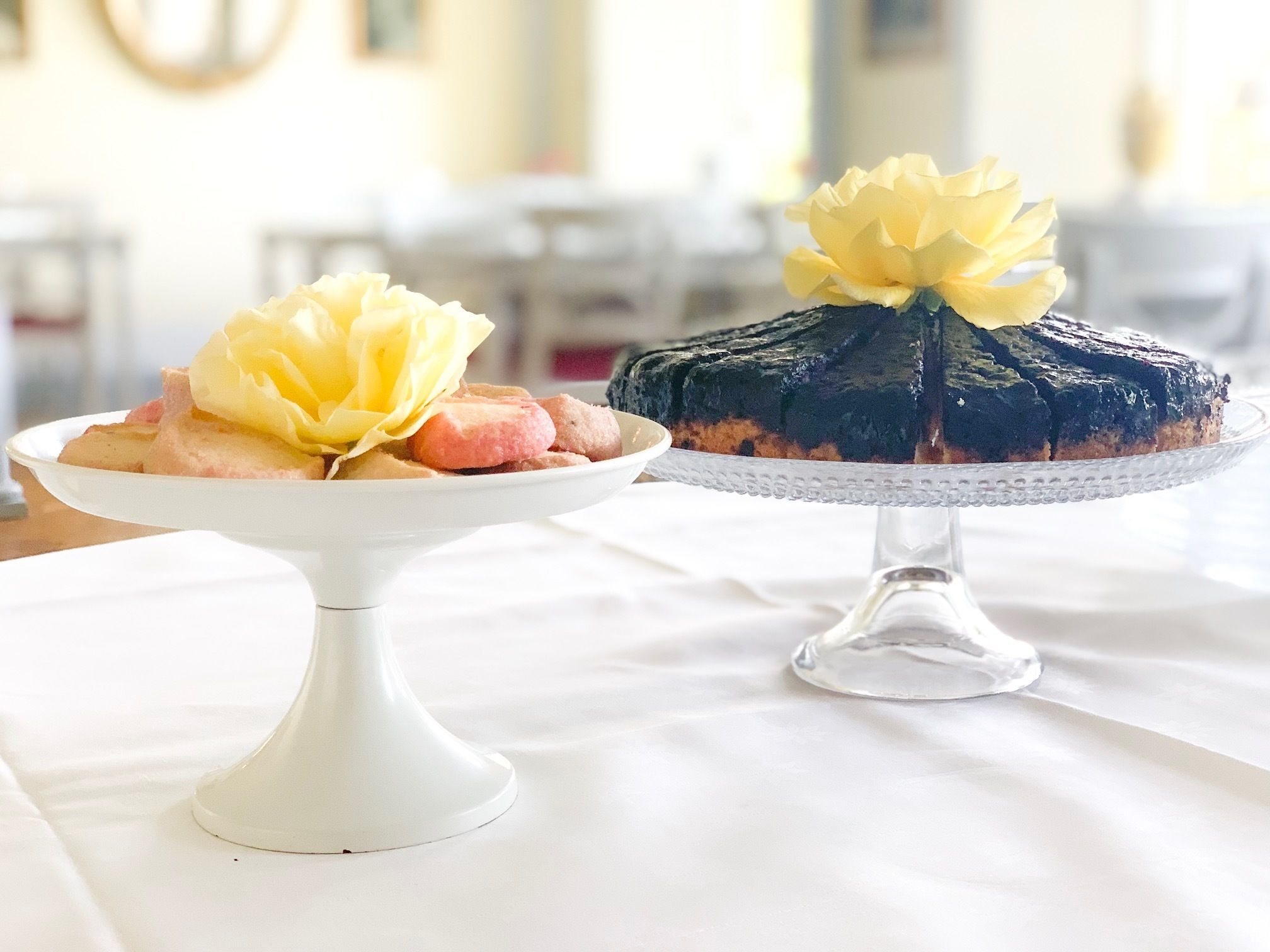 Due torte su piedistalli bianchi su un tavolo.