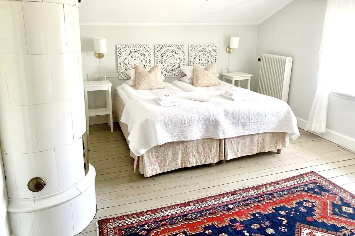 A bedroom with a bed, bedside tables, a radiator, and a patterned rug.