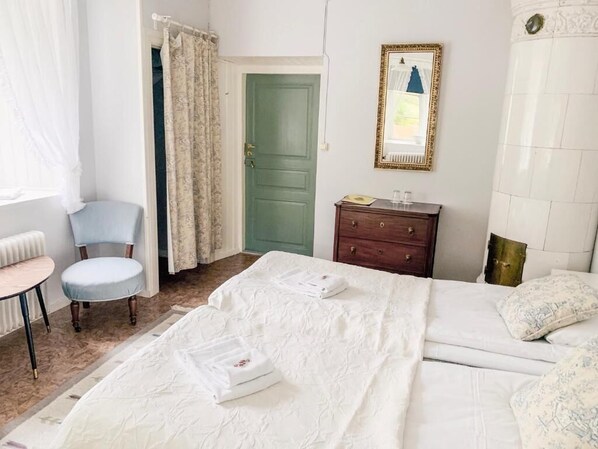 A bedroom with a bed, a chair, a dresser, and a door.