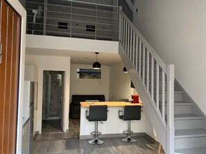 Eine moderne Küche mit Bar, einer Treppe und Blick auf den oberen Stock.